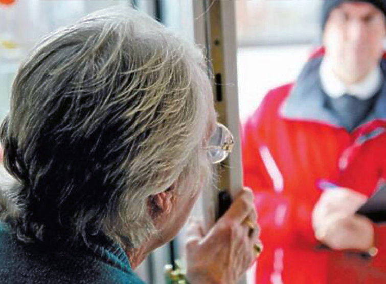 Persona anziana che apre la porta a un possibile truffatore vestito da incaricato a controlli