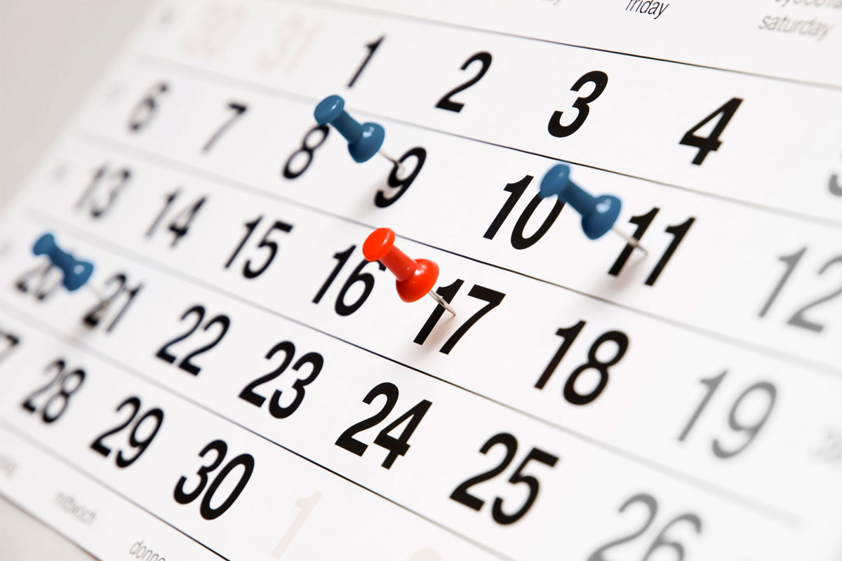 calendario con puntine di colore blu e rosso fissate su date